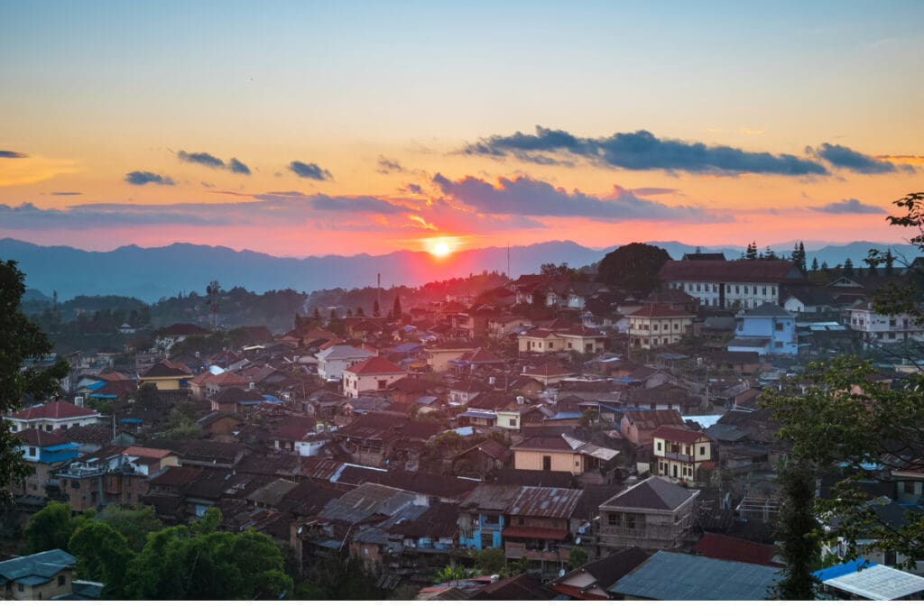 Hidden Places Around the World,View of a sunset over the town of Phongsali, Laos, with houses and mountains in the background.