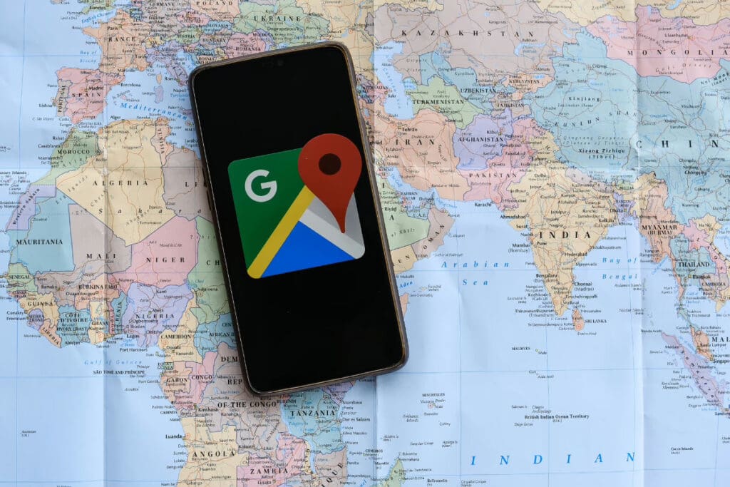 Travel on a Whim, A smartphone showing the Google Maps logo placed on a world map background.